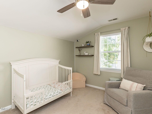 bedroom featuring vaulted ceiling, light carpet, baseboards, ceiling fan, and a crib
