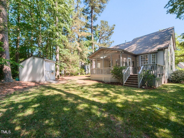 rear view of property with a storage shed, roof with shingles, an outbuilding, a lawn, and a sunroom