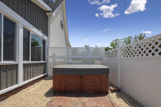 view of patio with a hot tub and fence