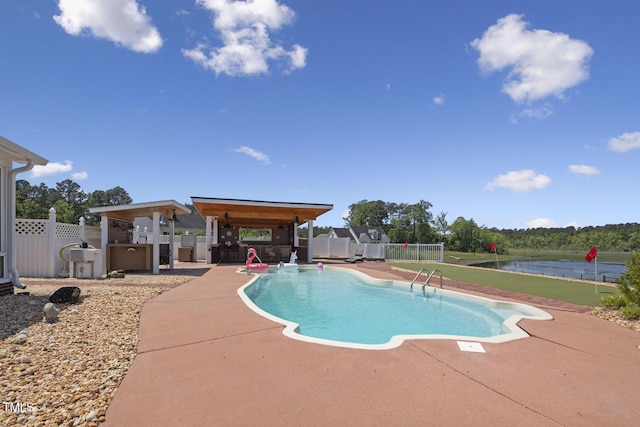 view of pool with a patio area, fence, and a water view