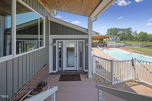 entrance to property featuring board and batten siding, a patio area, and fence