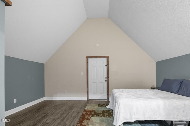 bedroom with wood finished floors, lofted ceiling, and baseboards