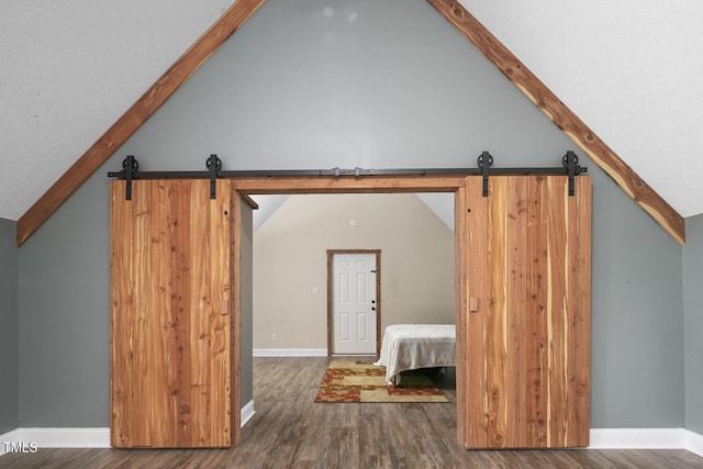 bonus room with a barn door, lofted ceiling, wood finished floors, and baseboards