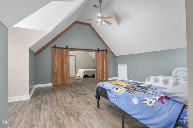 bedroom with wood finished floors, lofted ceiling, a barn door, a ceiling fan, and baseboards