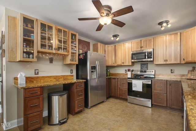 kitchen featuring appliances with stainless steel finishes, ceiling fan, light flooring, glass insert cabinets, and light stone counters