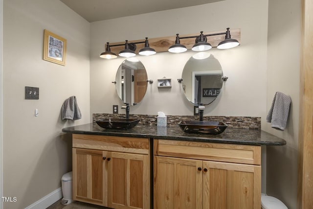 full bathroom featuring toilet, double vanity, and baseboards