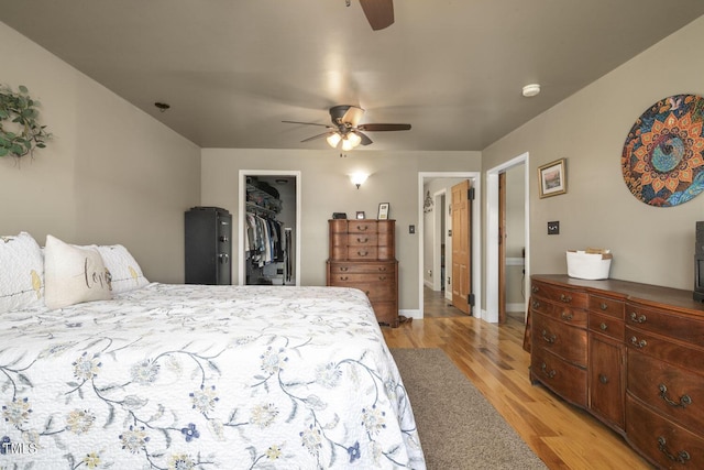 bedroom featuring light wood finished floors, a spacious closet, a closet, and a ceiling fan