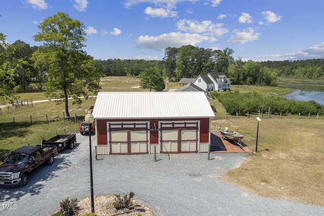 view of property's community featuring an outdoor structure, fence, a wooded view, a garage, and driveway