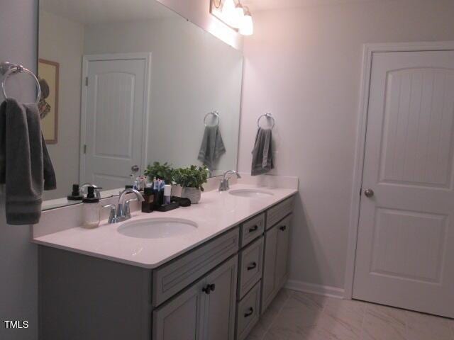 full bath featuring double vanity, a sink, and marble finish floor