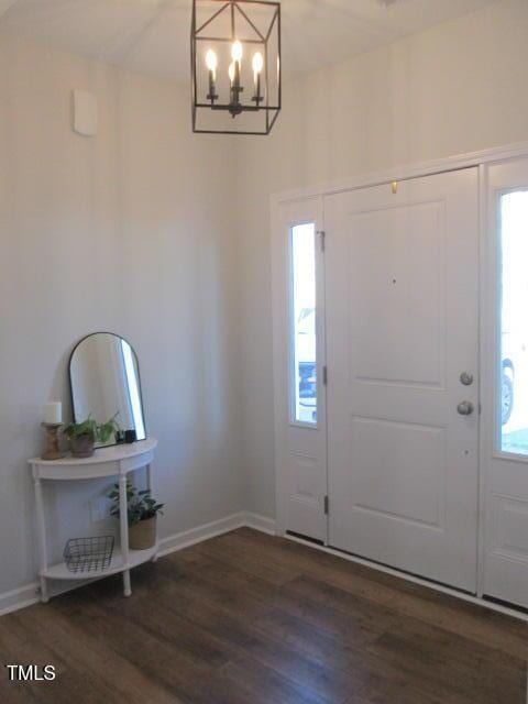 foyer with baseboards, wood finished floors, and a notable chandelier