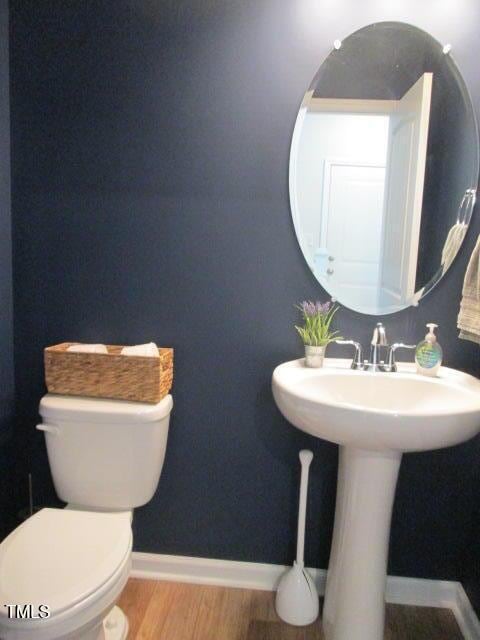 bathroom with baseboards, toilet, and wood finished floors