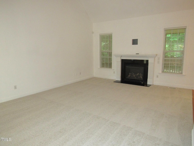 unfurnished living room with baseboards, a fireplace with flush hearth, and carpet