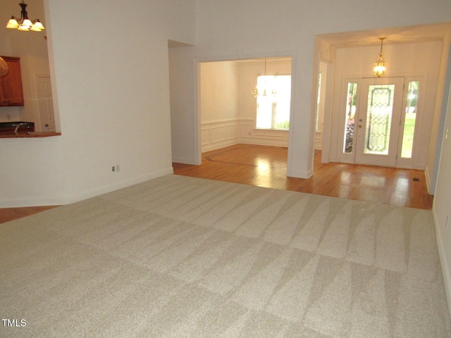 foyer entrance featuring baseboards, carpet flooring, wood finished floors, and a notable chandelier