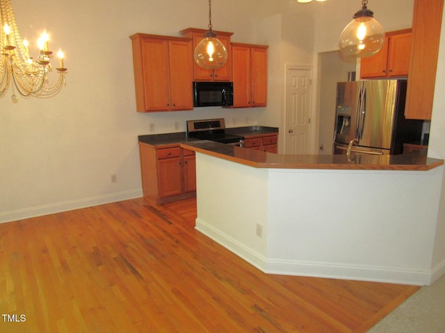 kitchen featuring an inviting chandelier, light wood finished floors, stainless steel appliances, baseboards, and pendant lighting