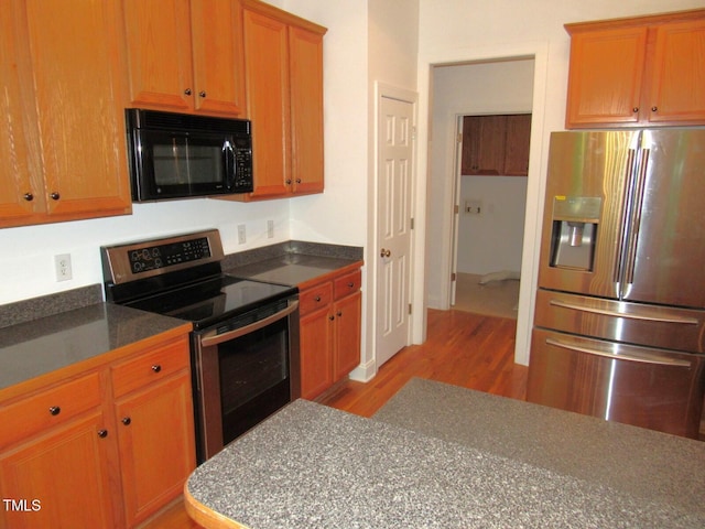 kitchen featuring dark countertops, stainless steel appliances, and light wood-style flooring