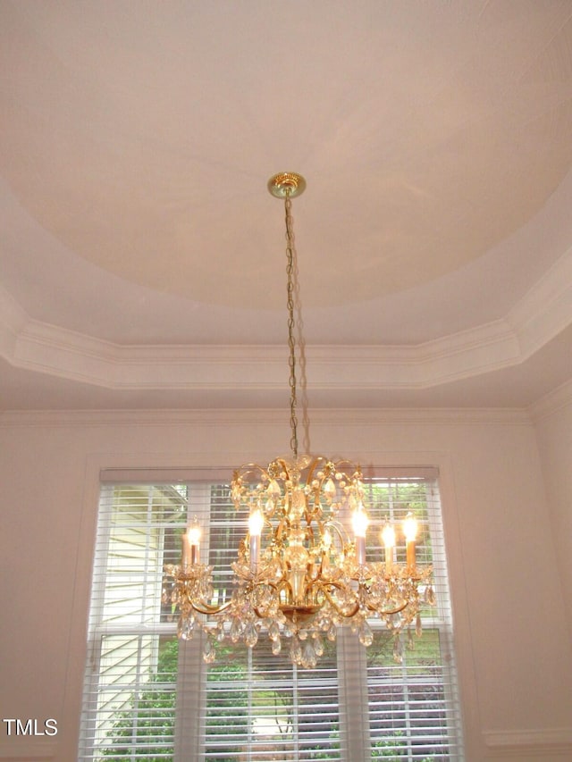 room details with crown molding, a raised ceiling, and a chandelier
