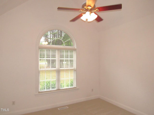 carpeted spare room featuring a healthy amount of sunlight, baseboards, ceiling fan, and visible vents