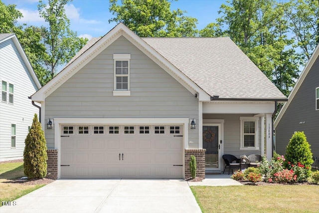 view of front of home with a shingled roof, concrete driveway, and brick siding