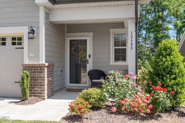 property entrance featuring a garage, covered porch, and brick siding