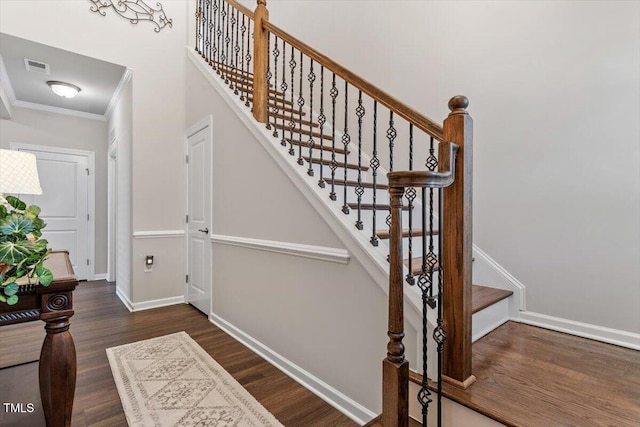 stairs featuring visible vents, ornamental molding, baseboards, and wood finished floors