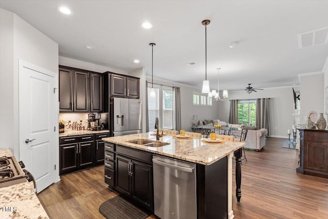 kitchen with a breakfast bar, a sink, stainless steel appliances, open floor plan, and dark wood-style floors