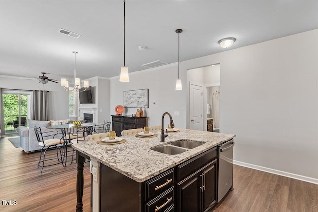 kitchen featuring dark wood-style flooring, decorative light fixtures, dishwasher, a sink, and open floor plan