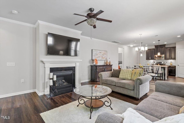 living area with baseboards, dark wood finished floors, and ceiling fan with notable chandelier