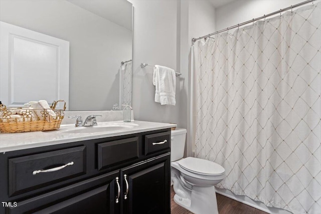 bathroom featuring a shower with shower curtain, toilet, wood finished floors, and vanity