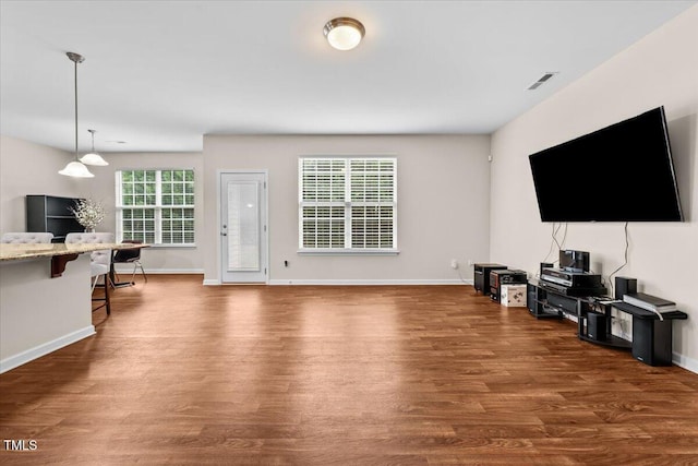 living area with baseboards, wood finished floors, and visible vents