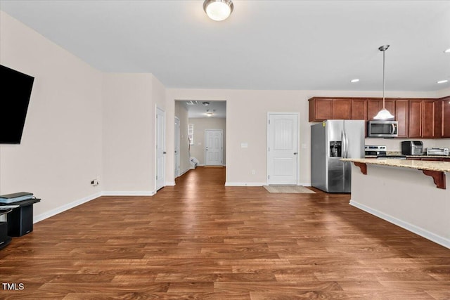 kitchen with a kitchen breakfast bar, baseboards, appliances with stainless steel finishes, and dark wood-type flooring