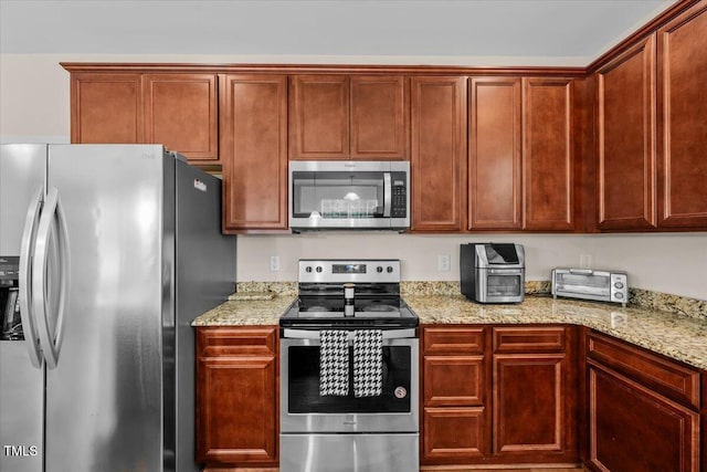 kitchen with stainless steel appliances, light stone countertops, and a toaster