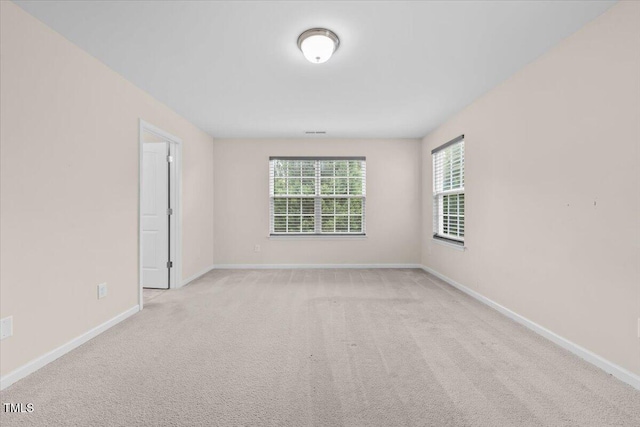 carpeted empty room featuring baseboards
