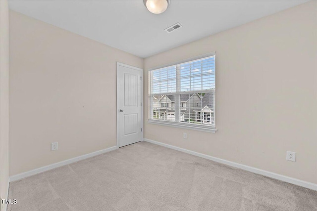 empty room with carpet floors, baseboards, and visible vents
