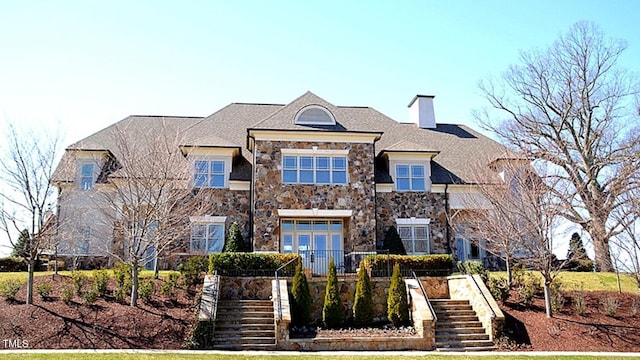 view of front of house featuring stairway, a chimney, and stone siding