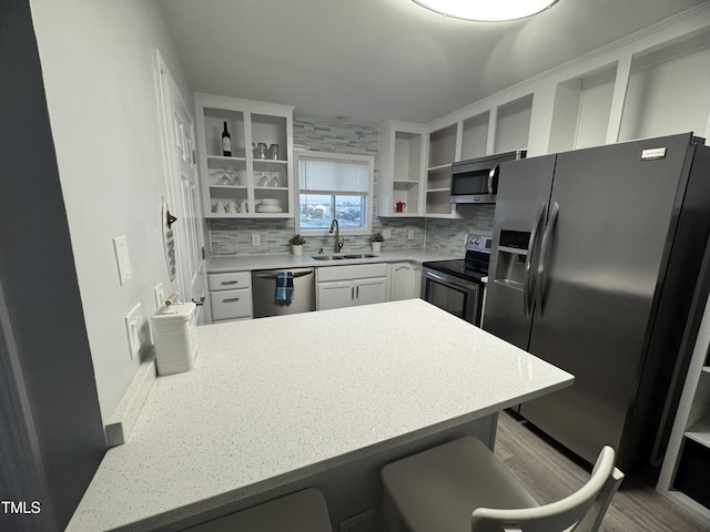 504 Carolina Beach Ave S Unit 2L, Carolina Beach, NC 28428 - kitchen with stainless steel appliances, open shelves, a sink, a peninsula, and tasteful backsplash