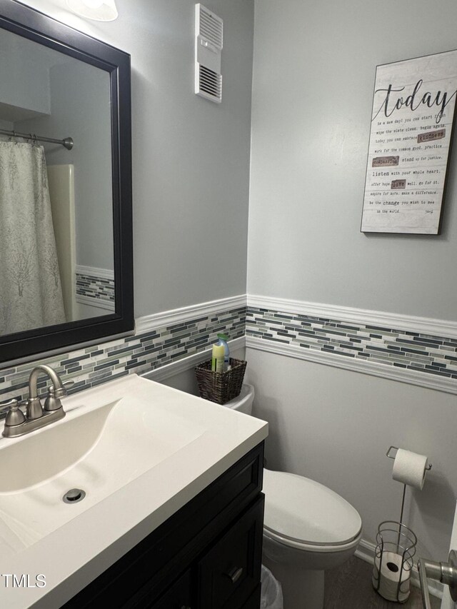 504 Carolina Beach Ave S Unit 2L, Carolina Beach, NC 28428 - bathroom with toilet, vanity, tile walls, a wainscoted wall, and curtained shower