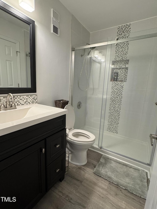 504 Carolina Beach Ave S Unit 2L, Carolina Beach, NC 28428 - full bath featuring wood finished floors, vanity, toilet, tasteful backsplash, and a shower stall
