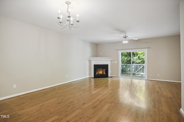 unfurnished living room featuring baseboards, a fireplace with flush hearth, wood finished floors, and ceiling fan with notable chandelier