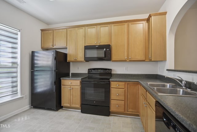 kitchen featuring plenty of natural light, a sink, baseboards, and black appliances
