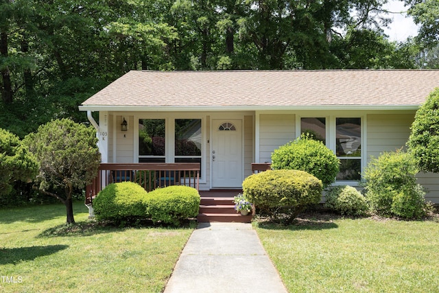 view of front of property with roof with shingles, covered porch, and a front lawn