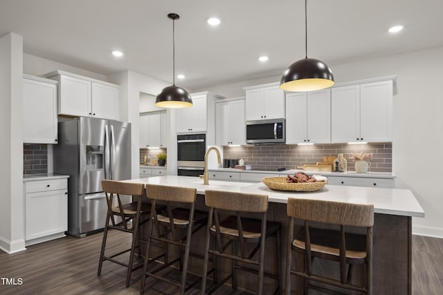 kitchen with a sink, decorative backsplash, stainless steel appliances, dark wood-type flooring, and light countertops