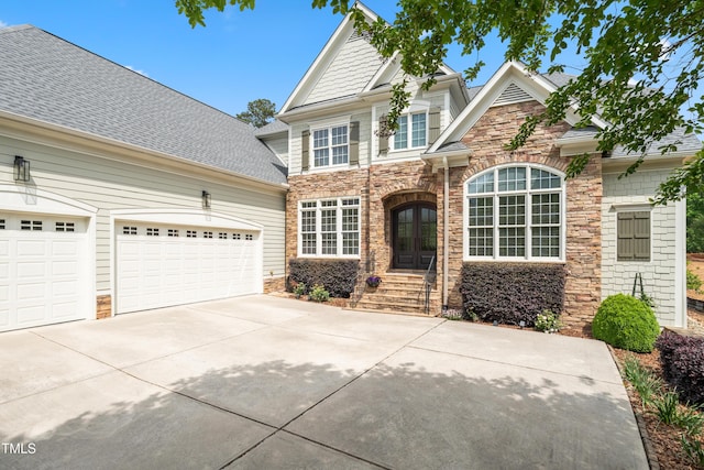 view of front of house featuring concrete driveway, roof with shingles, stone siding, and a garage