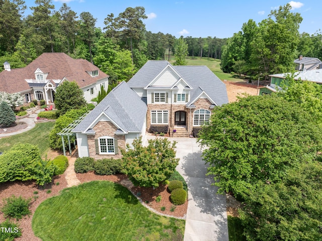 view of front of property featuring a pergola, driveway, a shingled roof, and stone siding