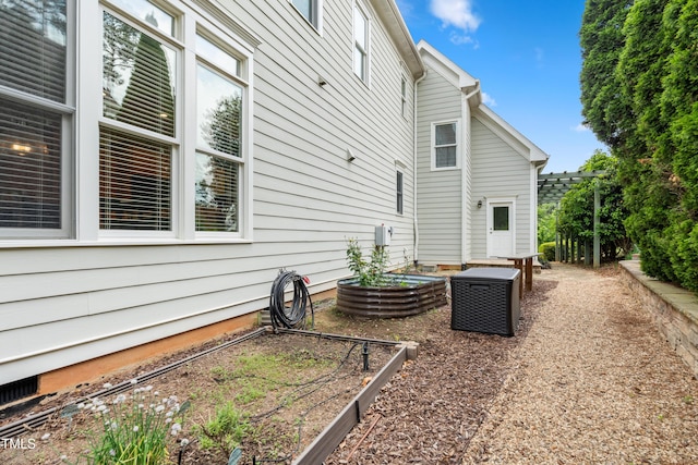 back of house featuring central AC unit and a vegetable garden