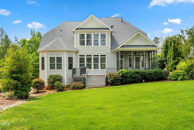 rear view of property featuring a lawn, a shingled roof, ceiling fan, and a sunroom