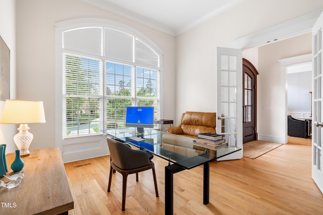 home office featuring plenty of natural light, ornamental molding, french doors, and light wood-style floors
