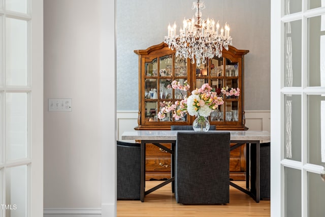 bar featuring an inviting chandelier, wainscoting, a decorative wall, and wood finished floors
