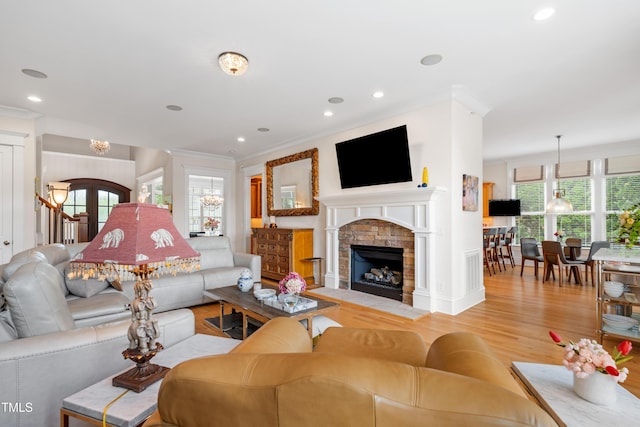 living area with light wood-style floors, ornamental molding, a fireplace, and recessed lighting