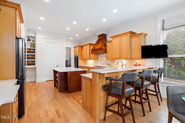 kitchen featuring ornamental molding, decorative backsplash, a peninsula, freestanding refrigerator, and custom range hood