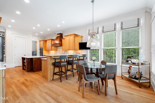 dining room featuring light wood-style floors, ornamental molding, baseboards, and recessed lighting